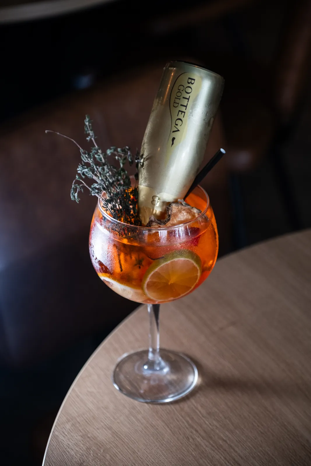 An orange cocktail with a sparkling wine bottle