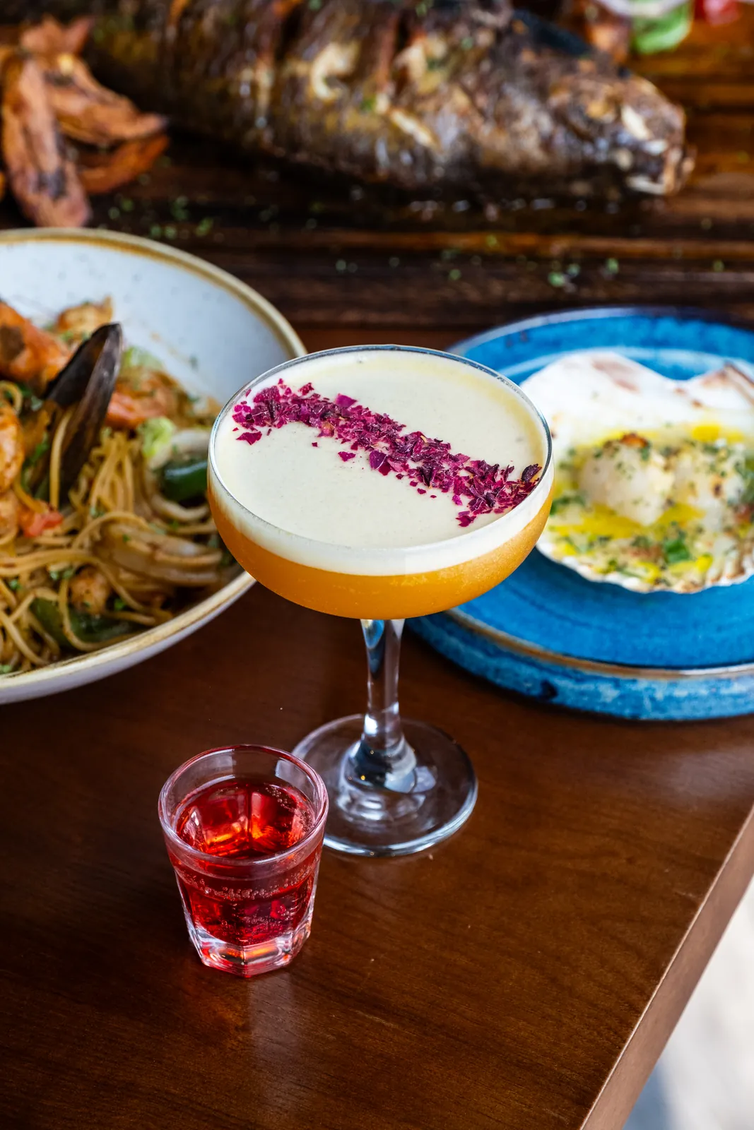 A cocktail alongside a table of food