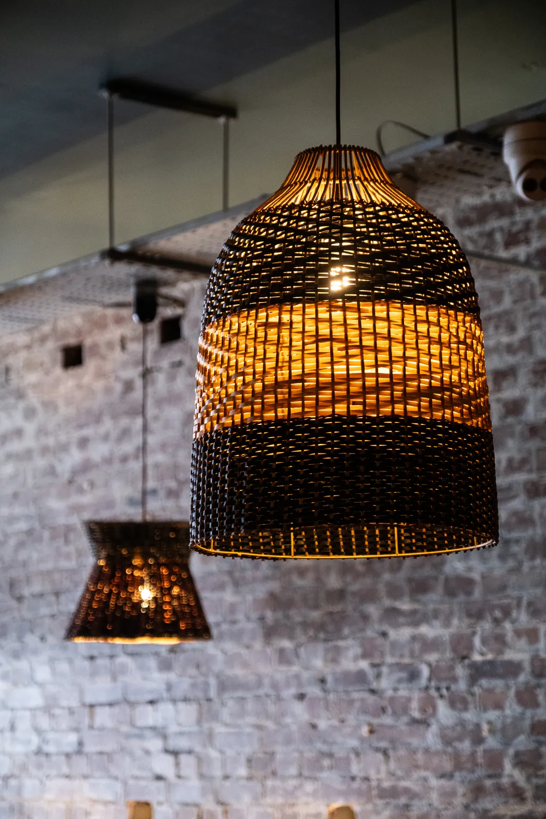 Woven pendant lighting against exposed brick